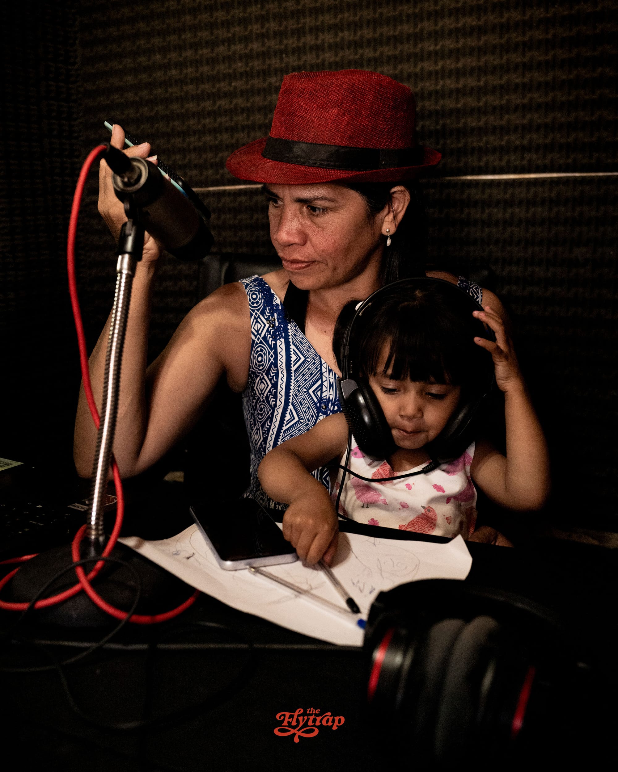 A woman in a sound booth with a child on her lap. 