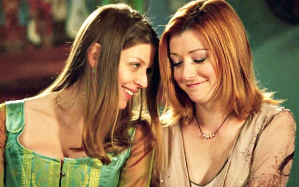 Screenshot: Tara, a white woman character with dark blond hair, leans affectionately into Willow, a white woman character with red hair